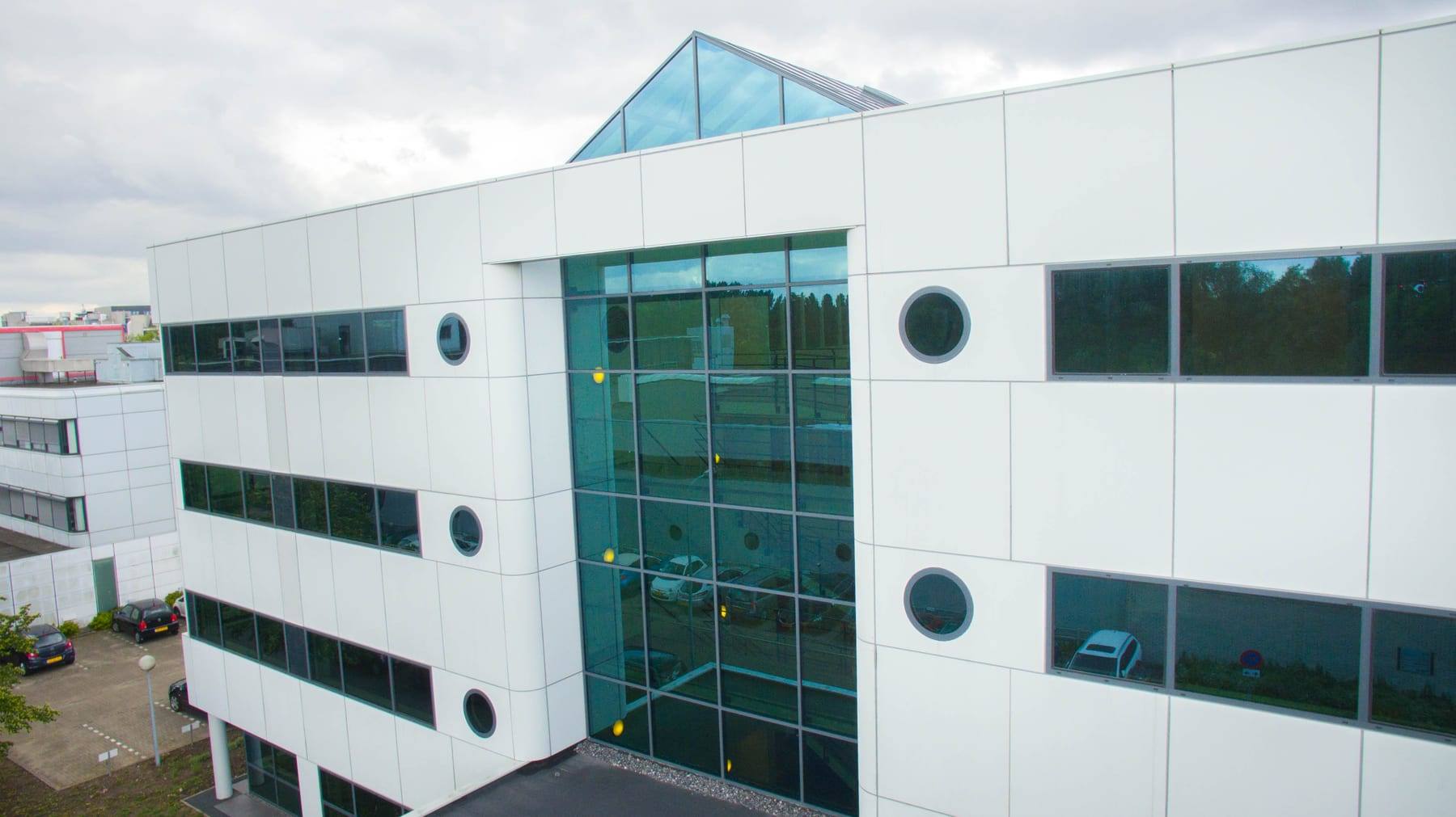 The same building from the air, close on the pitched glass roof over the atrium and the full-height window below it.