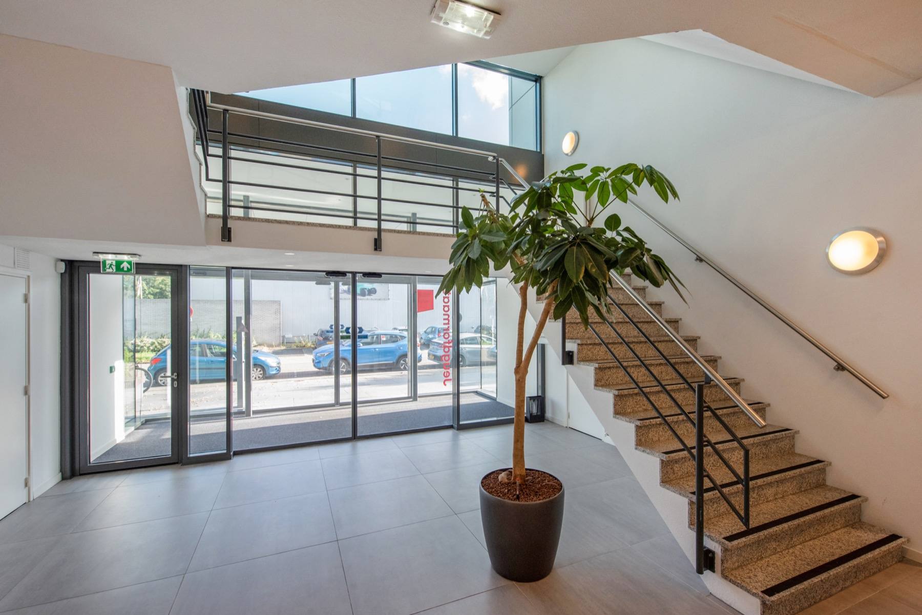 The entrance hall, with the staircase and the street beyond the glass doors.